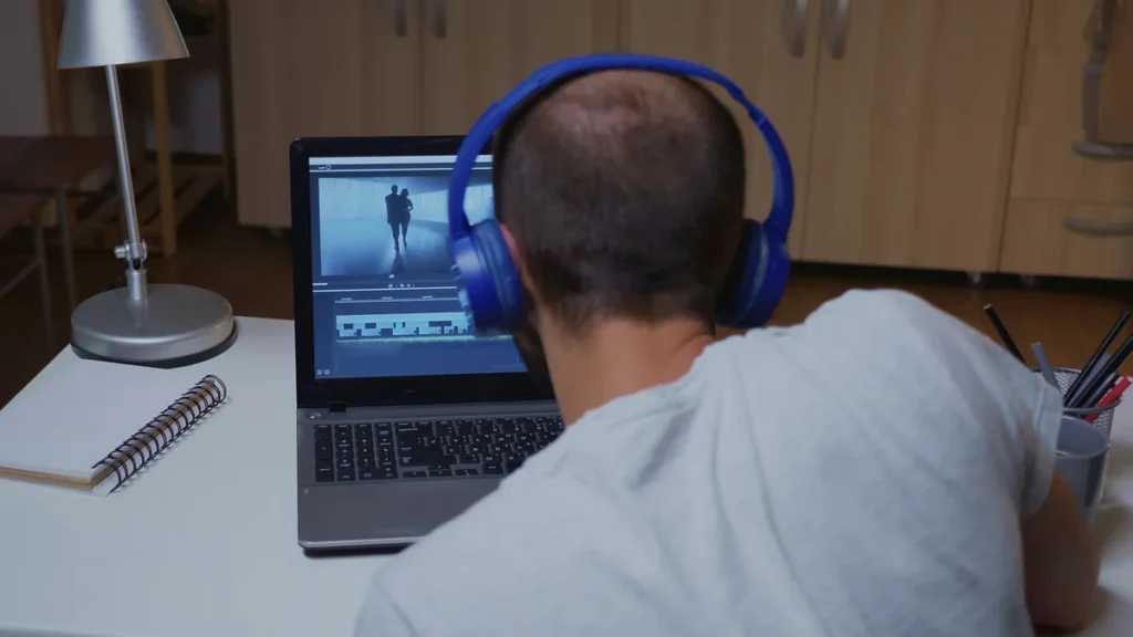 Monteur vidéo avec casque travaillant sur un logiciel de montage, pour convertir et télécharger des vidéos YouTube
