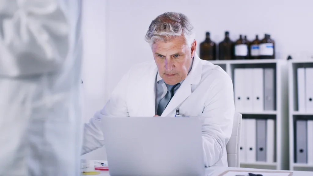 Chercheur en blouse blanche consultant sa messagerie sur un ordinateur portable dans un laboratoire