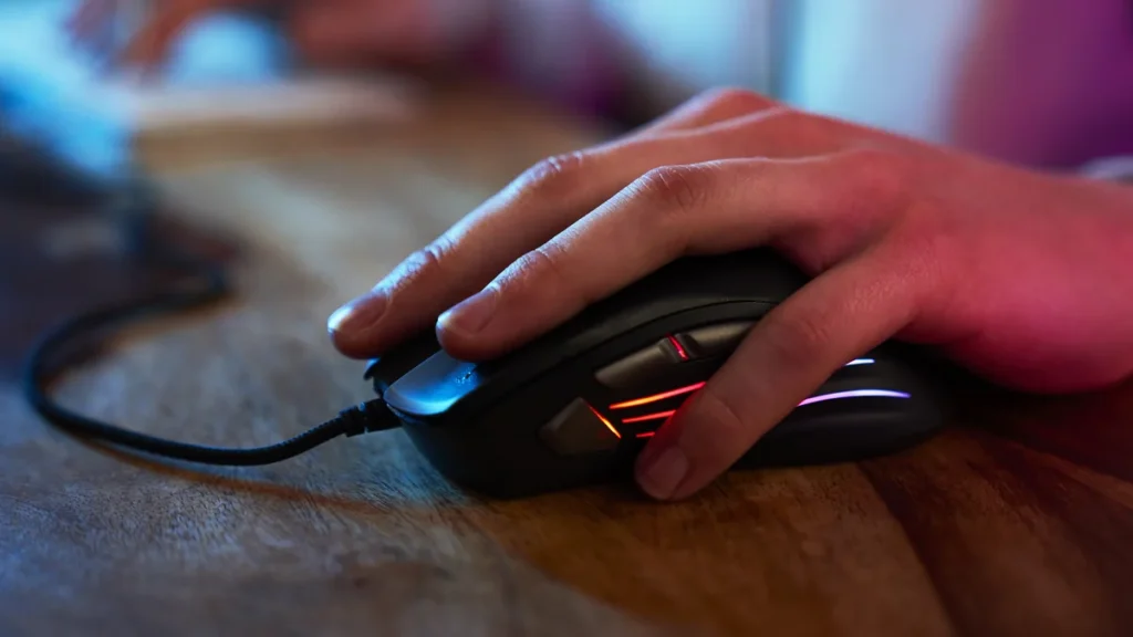 Main posée sur une souris gaming rétroéclairée RGB, idéale pour jouer à World of Warcraft