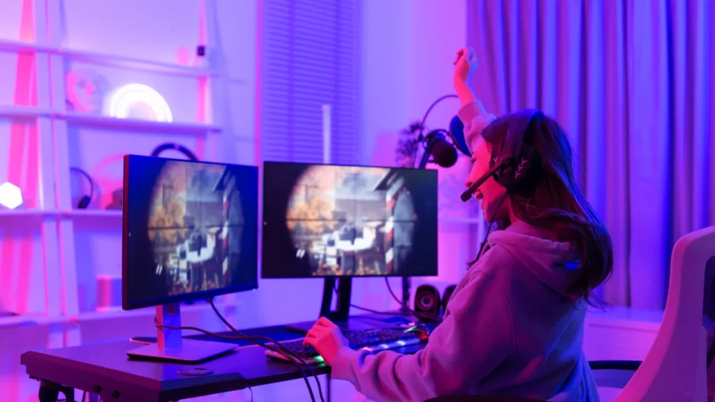 Joueuse enthousiaste devant deux écrans de PC gaming dans une chambre éclairée de néons violets