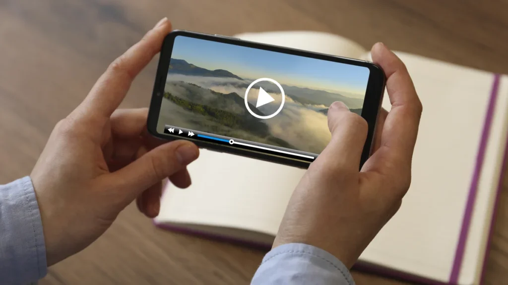 Mains tenant un smartphone à l’horizontale qui lit une vidéo de paysage, comme une vidéo TikTok téléchargée