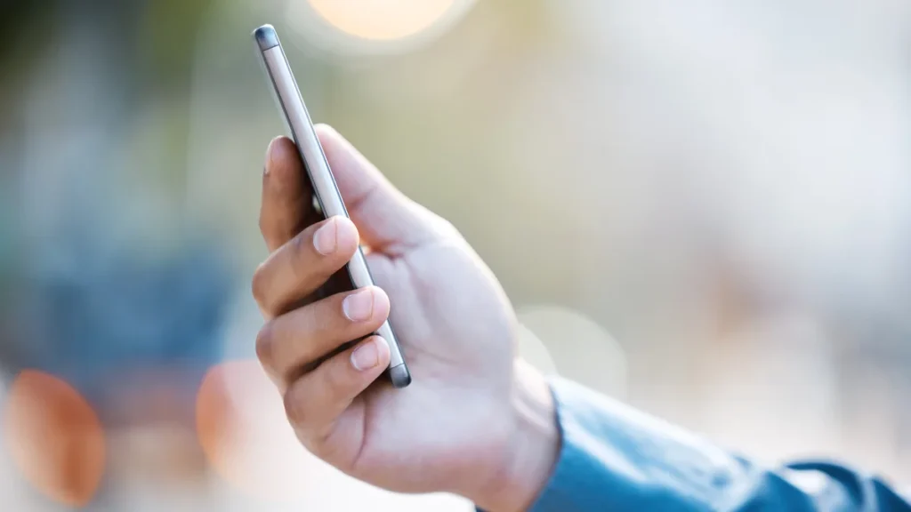 Main tenant un smartphone fin en extérieur, pour choisir un téléphone portable de 5 pouces