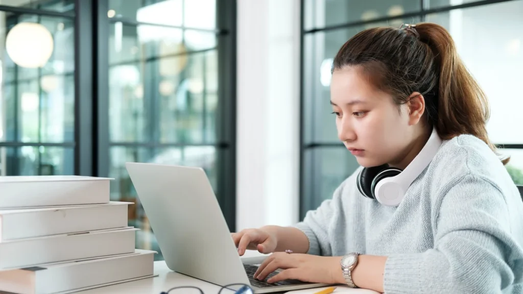 Jeune femme concentrée travaillant sur un ordinateur portable pour consulter le webmail de l’académie de Normandie