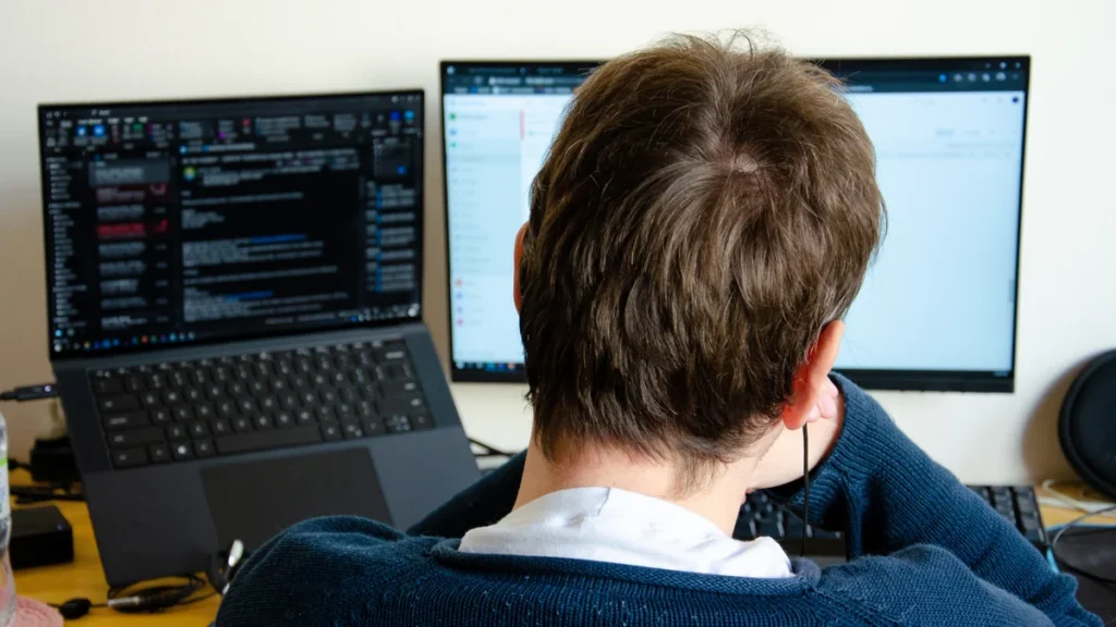 Homme travaillant sur un ordinateur portable et un second écran, pour faire tourner Windows sur Mac avec UTM